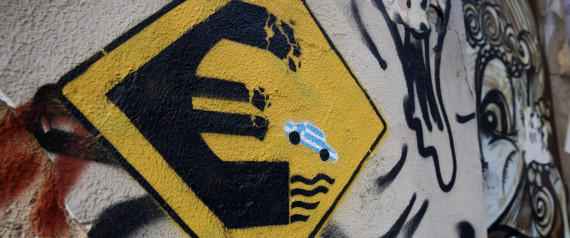 In this photo taken on Thursday, June 18, 2015 a stencil work by an artist who uses the name Wild Drawing shows a fake road sign with a little car in the blue and white Greek colours tumbling off a crumbling euro currency sign into the water. It’s called “Keep Away.” Over the past five years of Greece’s economic depression, more and more paintings comment on the country’s financial and social woes. (AP Photo/Petros Giannakouris)
