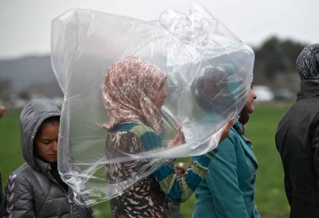 A migrant girl shields herself from the rain while waiting in a line for food rations at the northern Greek border station of Idomeni on March 7, 2016. Greek police officials say Macedonian authorities have imposed further restrictions on refugees trying to cross the border, saying only those from cities they consider to be at war can enter as up to 14,000 people are trapped in Idomeni, while another 6,000-7,000 are being housed in refugee camps around the region. (AP Photo/Vadim Ghirda)