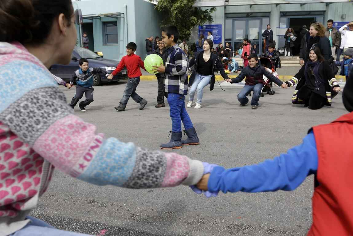 Greek pupils and their teacher play with refugee children in Piraeus, near Athens, Tuesday, March 8, 2016. European Union leaders hoped early Tuesday they reached the outlines for a possible deal with Ankara to return thousands of migrants to Turkey and said they were confident a full agreement could be reached at a summit next week. (AP Photo/Thanassis Stavrakis)