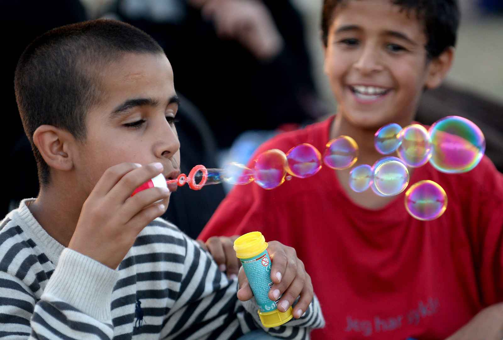 epaselect epa04937488 A migrant child blows bubbles made from soap and water while waiting at a registration camp after they crossed the border between Greece and Macedonia near the city of Gevgelija, The Former Yugoslav Republic of Macedonia, 18 September 2015. Thousands of migrants continue to arrive in Macedonia, on their way to Serbia, Croatia and EU countries. Hungary on 15 September sealed the last gap in the barricade along its border with Serbia, closing the passage to thousands of refugees and migrants still waiting on the other side.  EPA/Nake Batev
