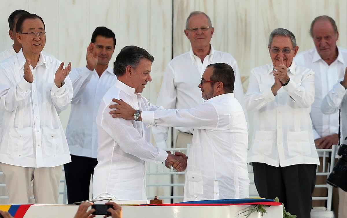 Colombia’s President Juan Manuel Santos, front left, and the top commander of the Revolutionary Armed Forces of Colombia (FARC) Rodrigo Londono, known by the alias Timochenko, shake hands after signing the peace agreement between Colombia’s government and the FARC to end over 50 years of conflict in Cartagena, Colombia, Monday, Sept. 26, 2016. Behind, from left, are U.N. Secretary General Ban Ki Moon, Mexico's President Enrique Pena Nieto, Peru's President Pedro Pablo Kuczynski, Cuba's President Raul Castro, and Spain's former King Juan Carlos. (AP Photo/Fernando Vergara)