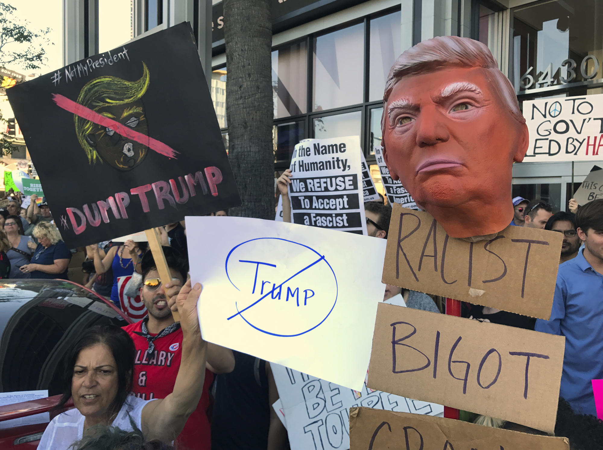 Protesters hold banners during a rally outside the CNN studios, in opposition to President-elect Donald Trump, in the Hollywood section of Los Angeles on Sunday, Nov .13, 2016. (AP Photo/Damian Dovarganes)
